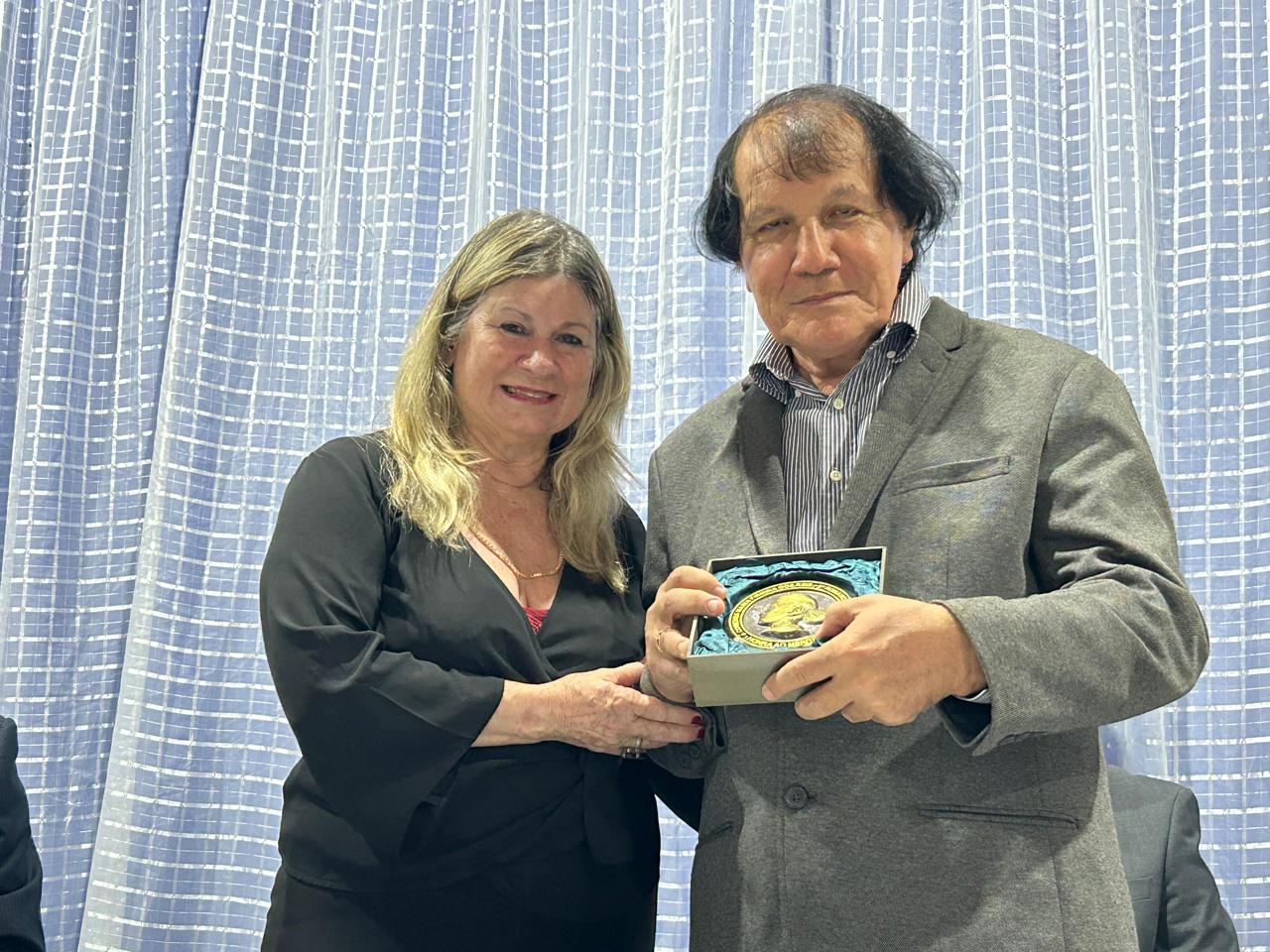 A Profª Dilercy Adler entrega a medalha e o diploma ao escritor José Ewerton Neto, membro da AML – Foto: Iago Azevedo