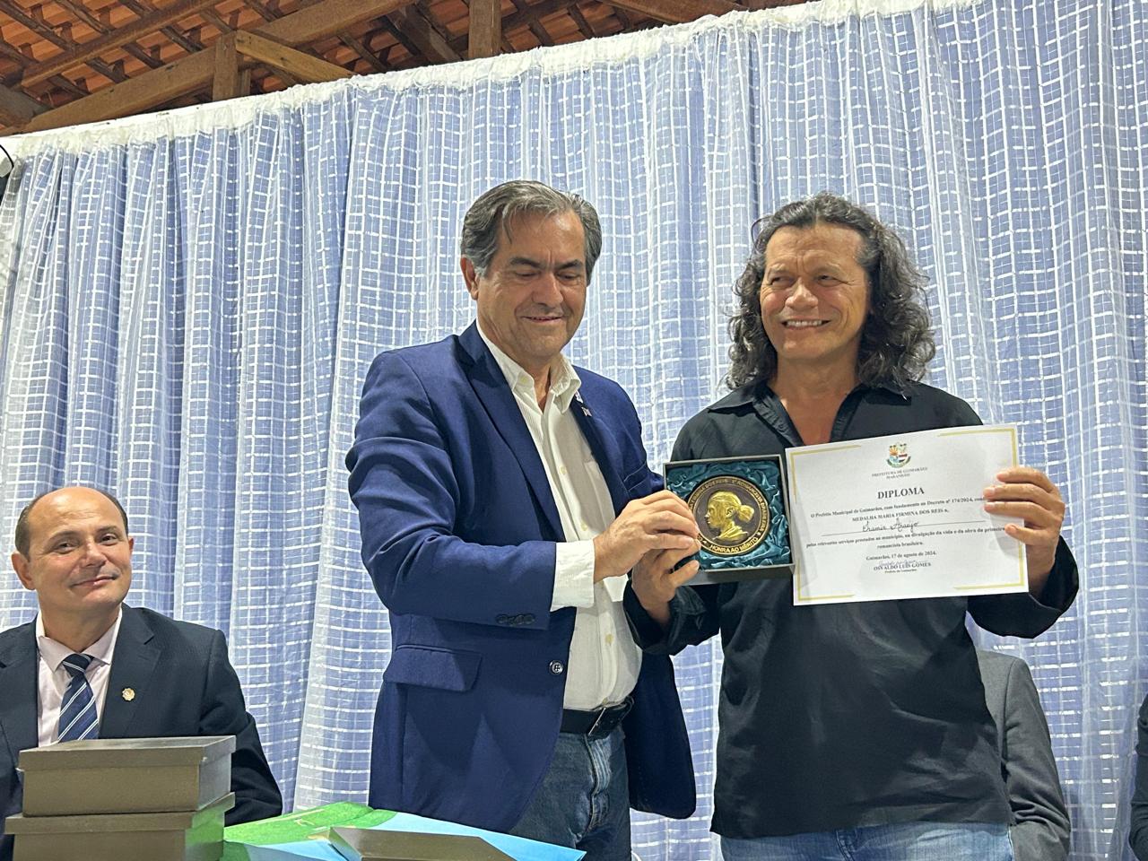 O subsecretário estadual de Turismo, Luiz Thadeu Nunes e Silva entrega a medalha e o diploma ao escritor Iramir Araújo